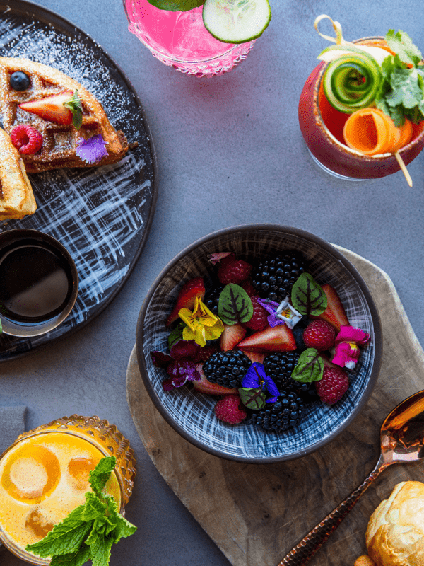 tablescape of breakfast foods including waffles and fruit salad