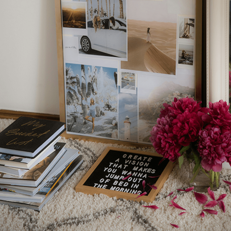 A vision board set on a table with books and flowers