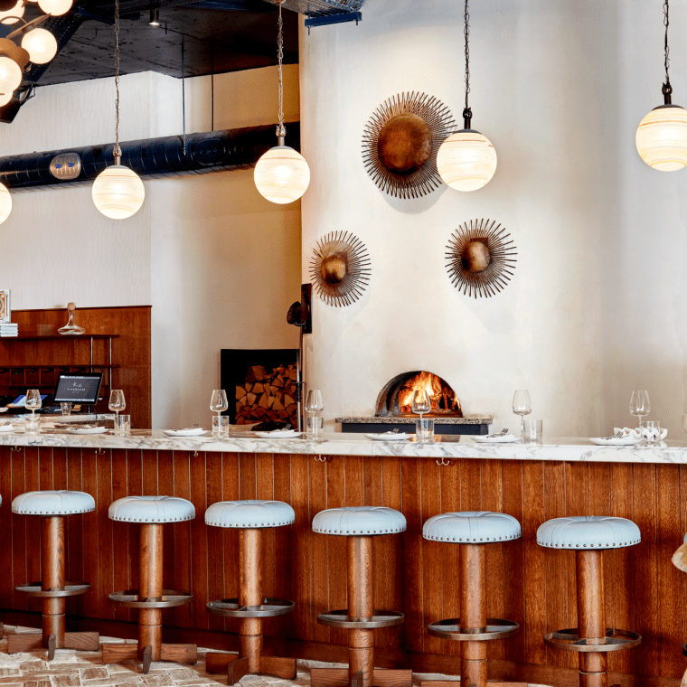 A wood-fired pizza oven behind bar seating at Pizzeria Mozza
