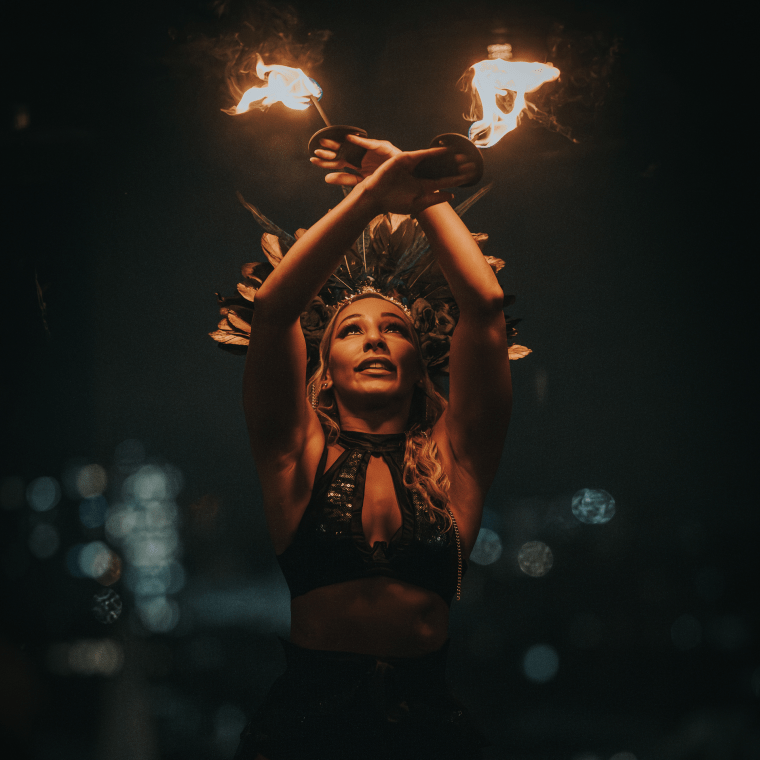 A woman dances with fire above her head.