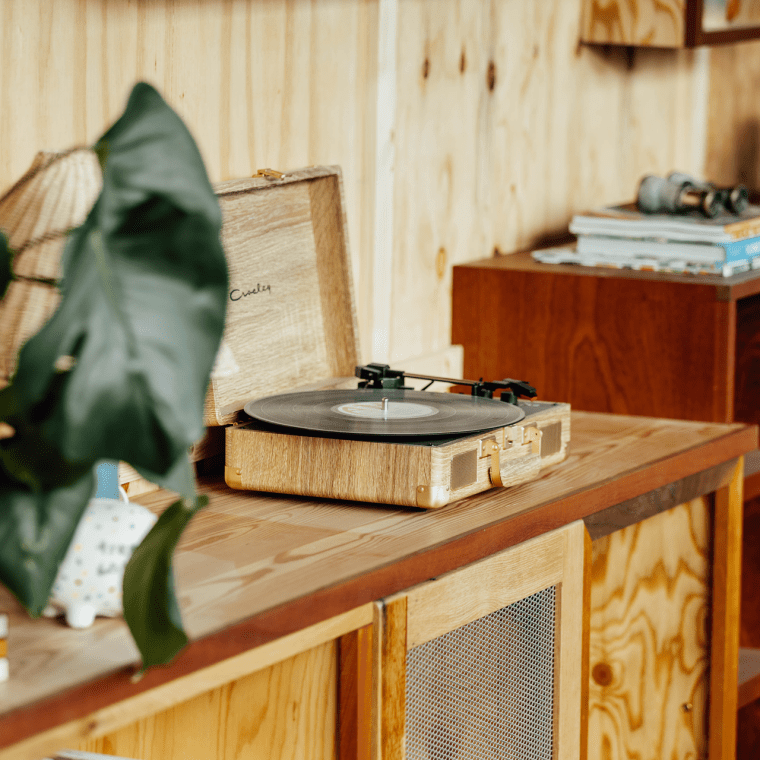 A record player on a shelf with large green plants and knick knacks in a suite at Treehouse Manchester.