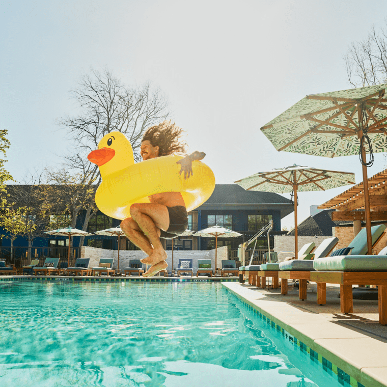 Person jumping into pool with float
