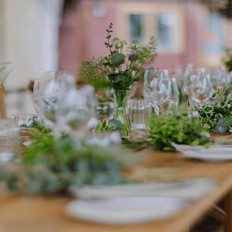 A table set for a wedding reception with greenery 