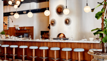 A wood-fired pizza oven behind bar seating at Pizzeria Mozza