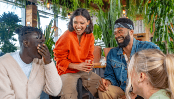 A group of friends sitting in a plant filled area of Treehouse Hotel laughing.