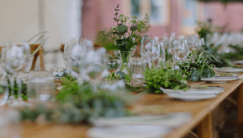 A table set for a wedding reception with greenery 