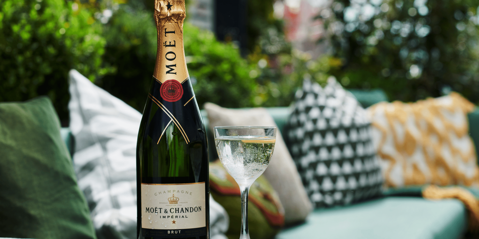 A bottle and glass of Moet & Chandon resting on the ledge of a patio sofa
