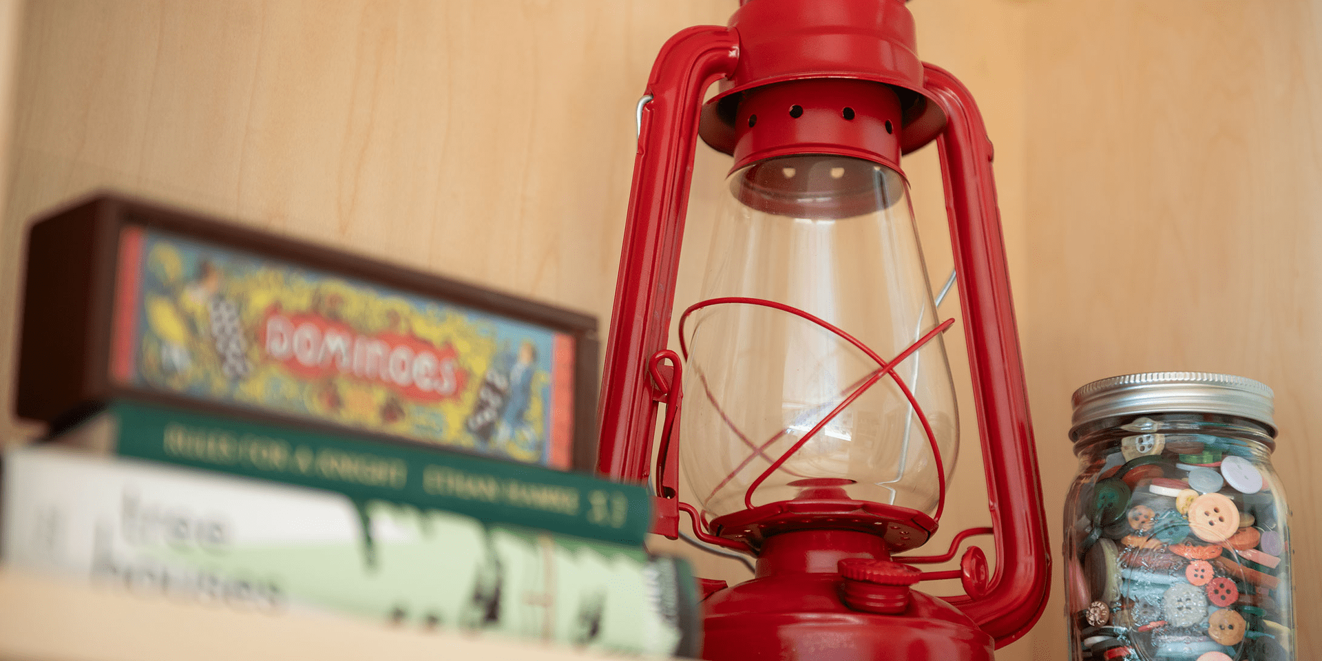 various objects displayed on a shelf including a red lantern and a mason jar full of buttons