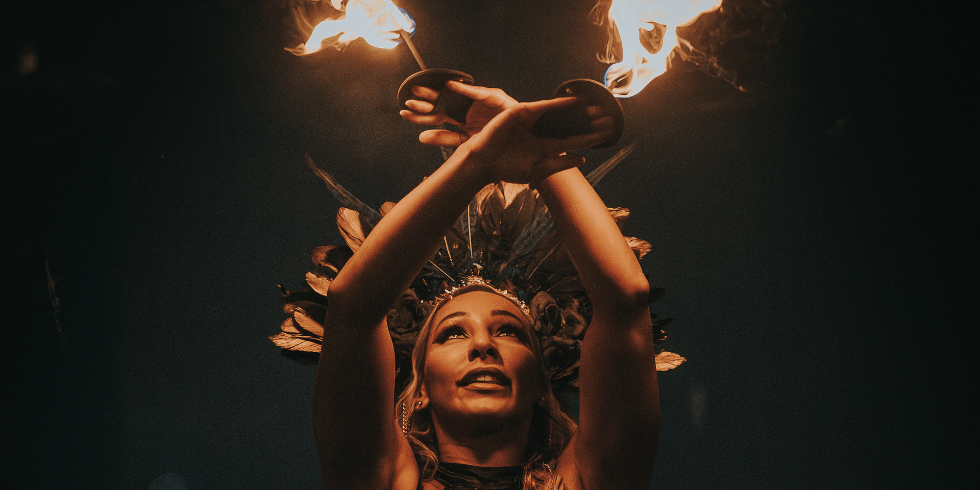 A woman dances with fire above her head.
