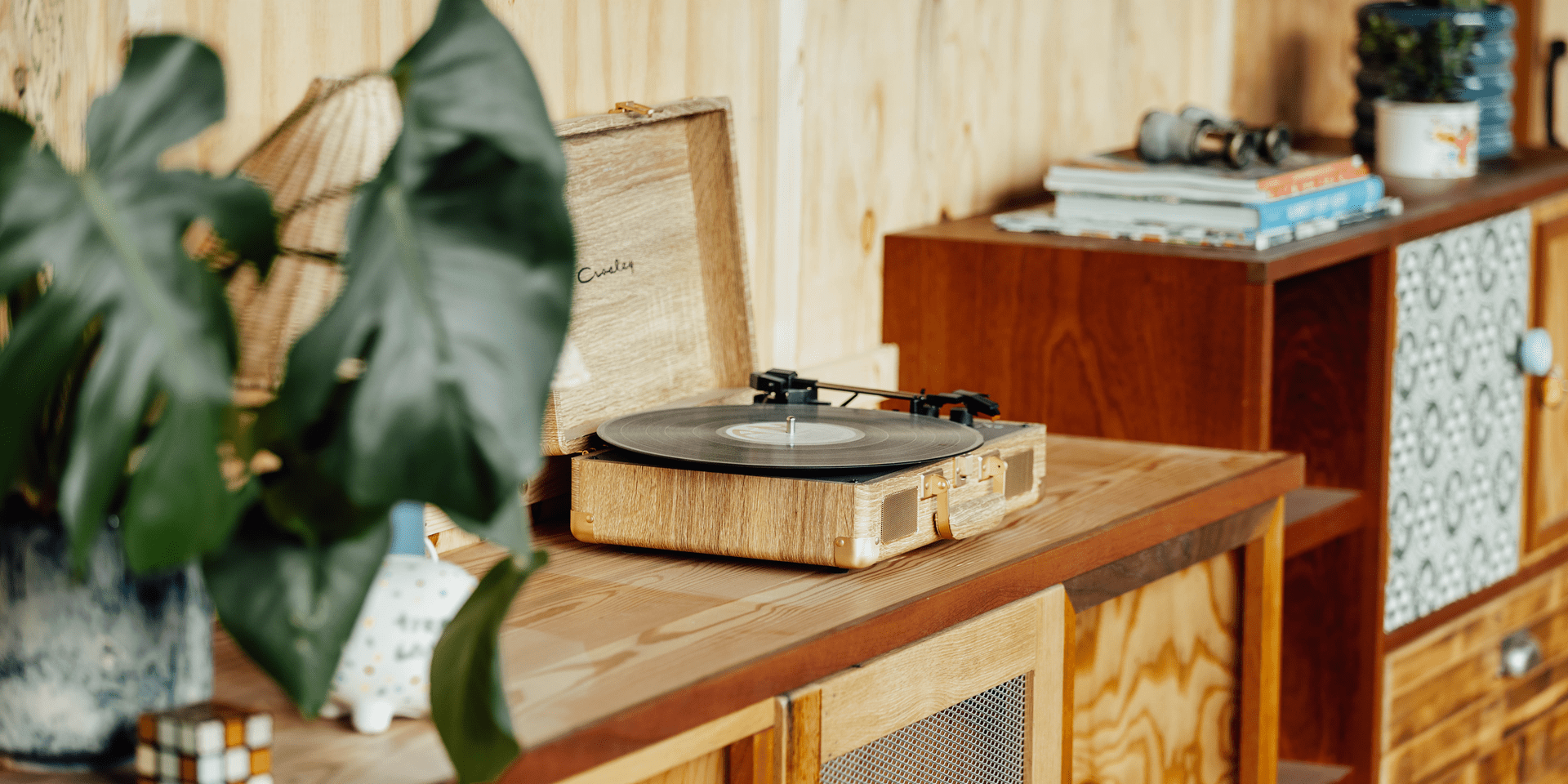 A record player on a shelf with large green plants and knick knacks in a suite at Treehouse Manchester.