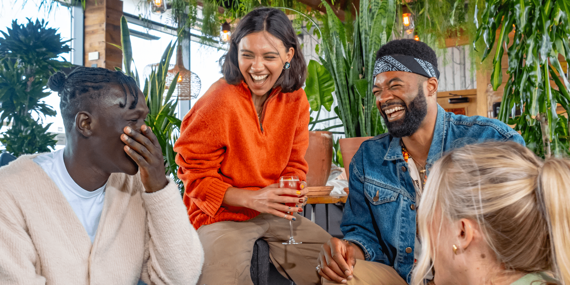 A group of friends sitting in a plant filled area of Treehouse Hotel laughing.