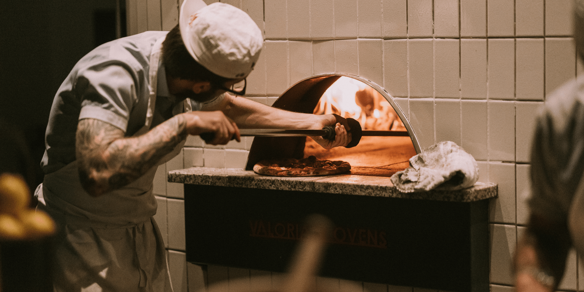 Pizza chef putting pizza into an oven
