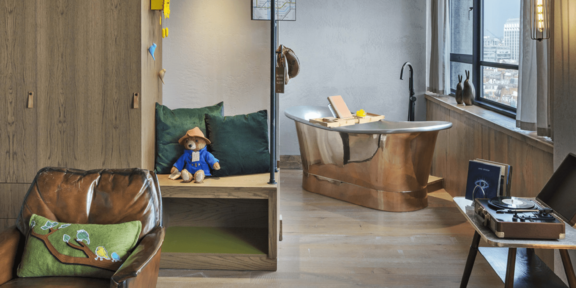 paddington bear sitting on a small bench with a bathtub in the background