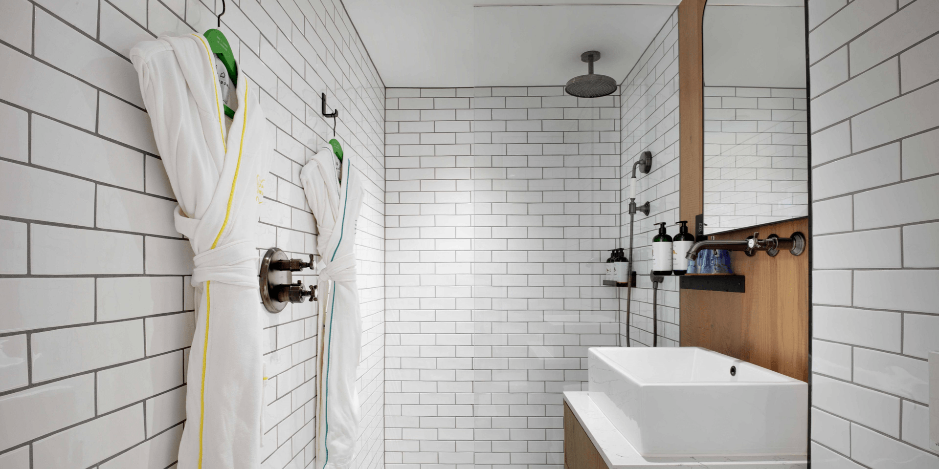 Bathroom with white tiles and robes hanging up