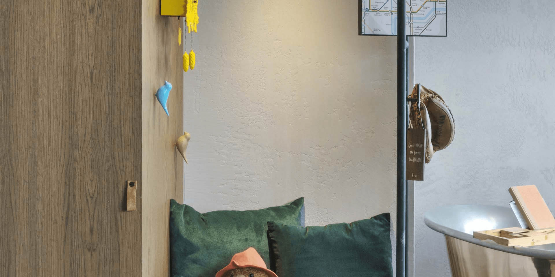 paddington bear sitting on a small bench with a bathtub in the background