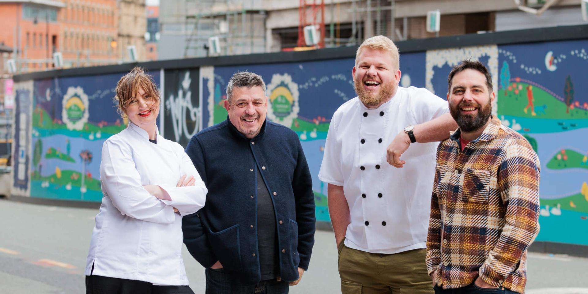 Chefs at Treehouse Manchester posing and smiling together in front of a street art mural