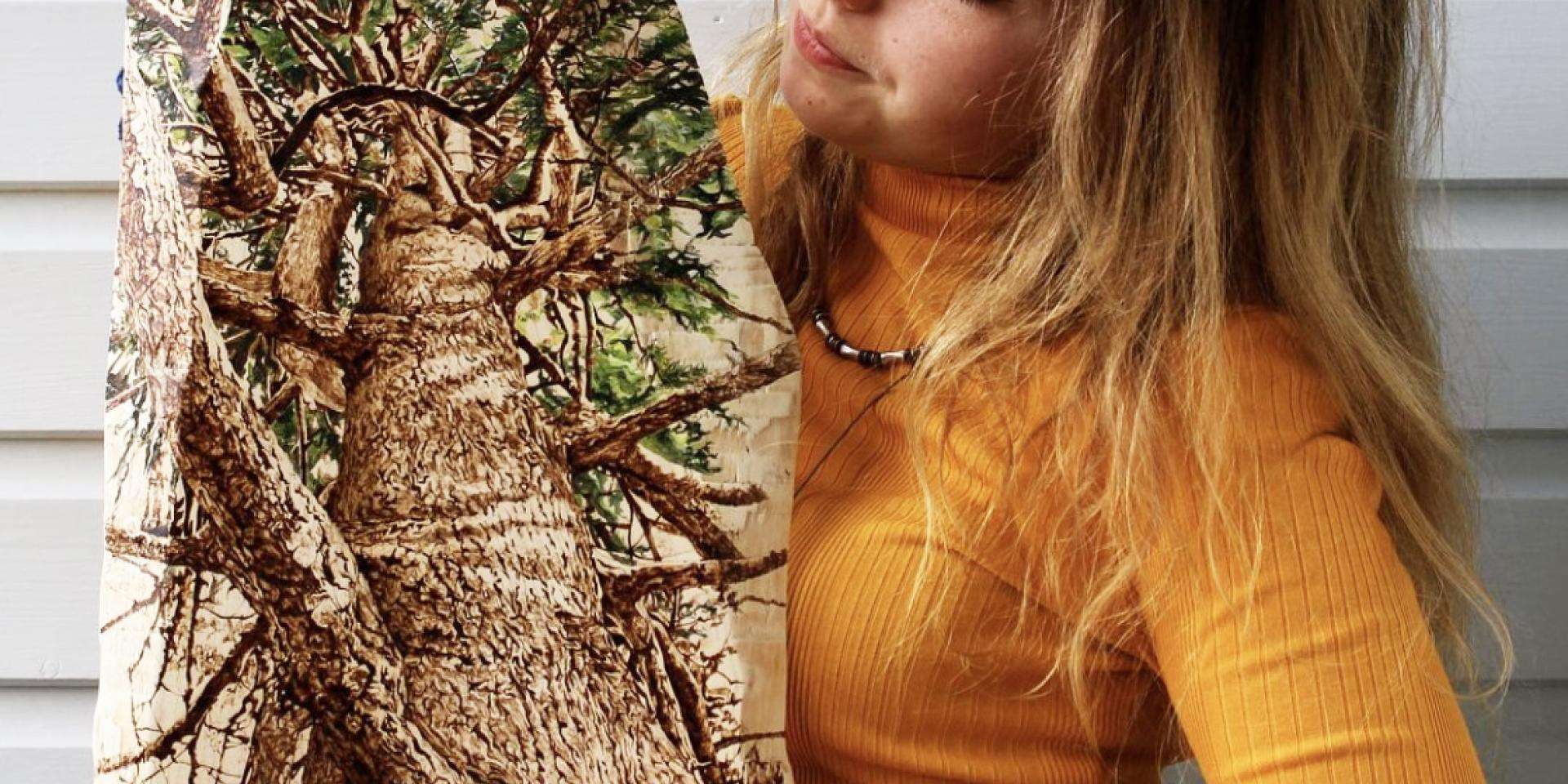 Tilia Holmes holding a painting of a tree